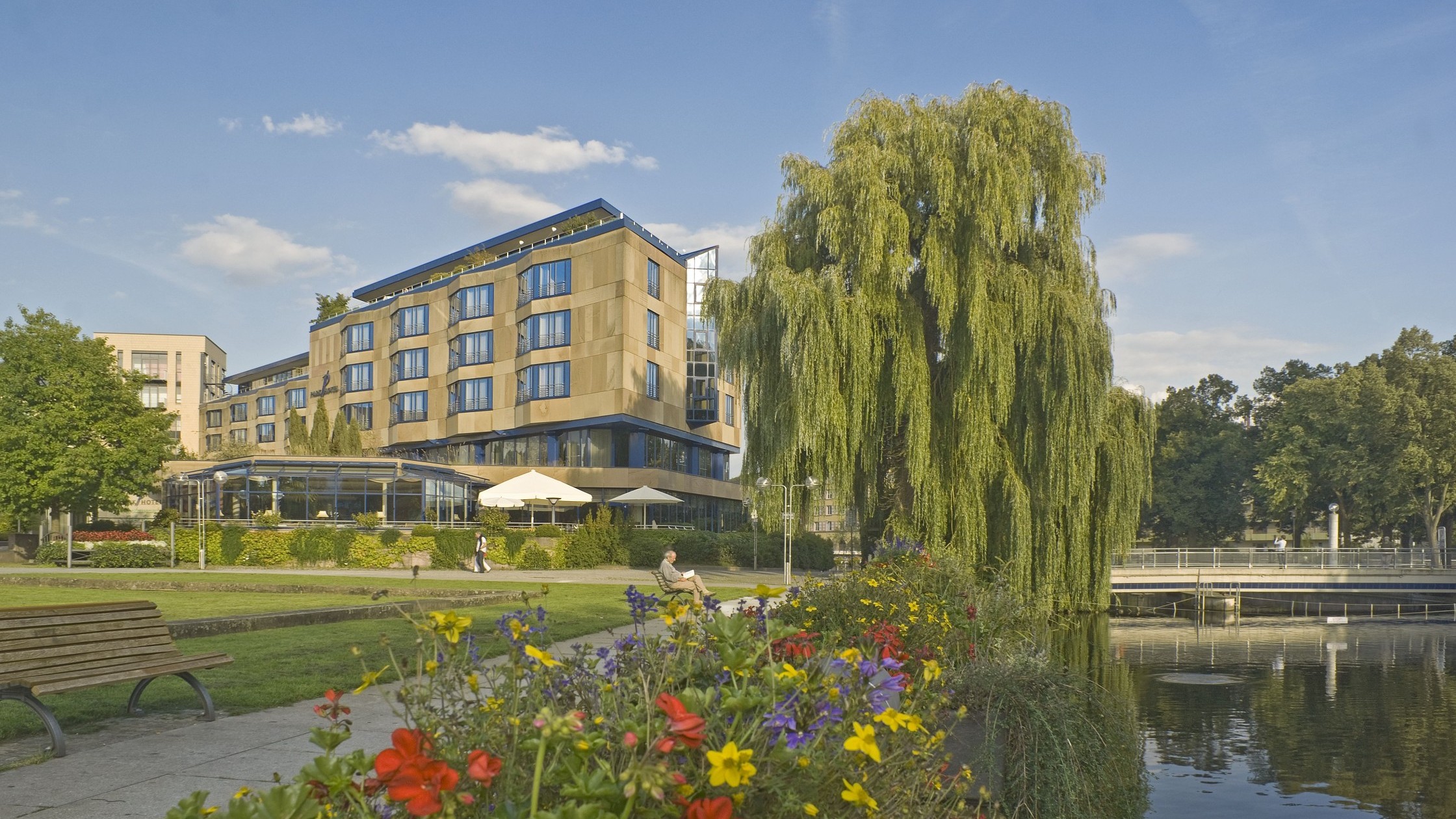 Aussenansicht Hotel mit Blumen und großen Weide