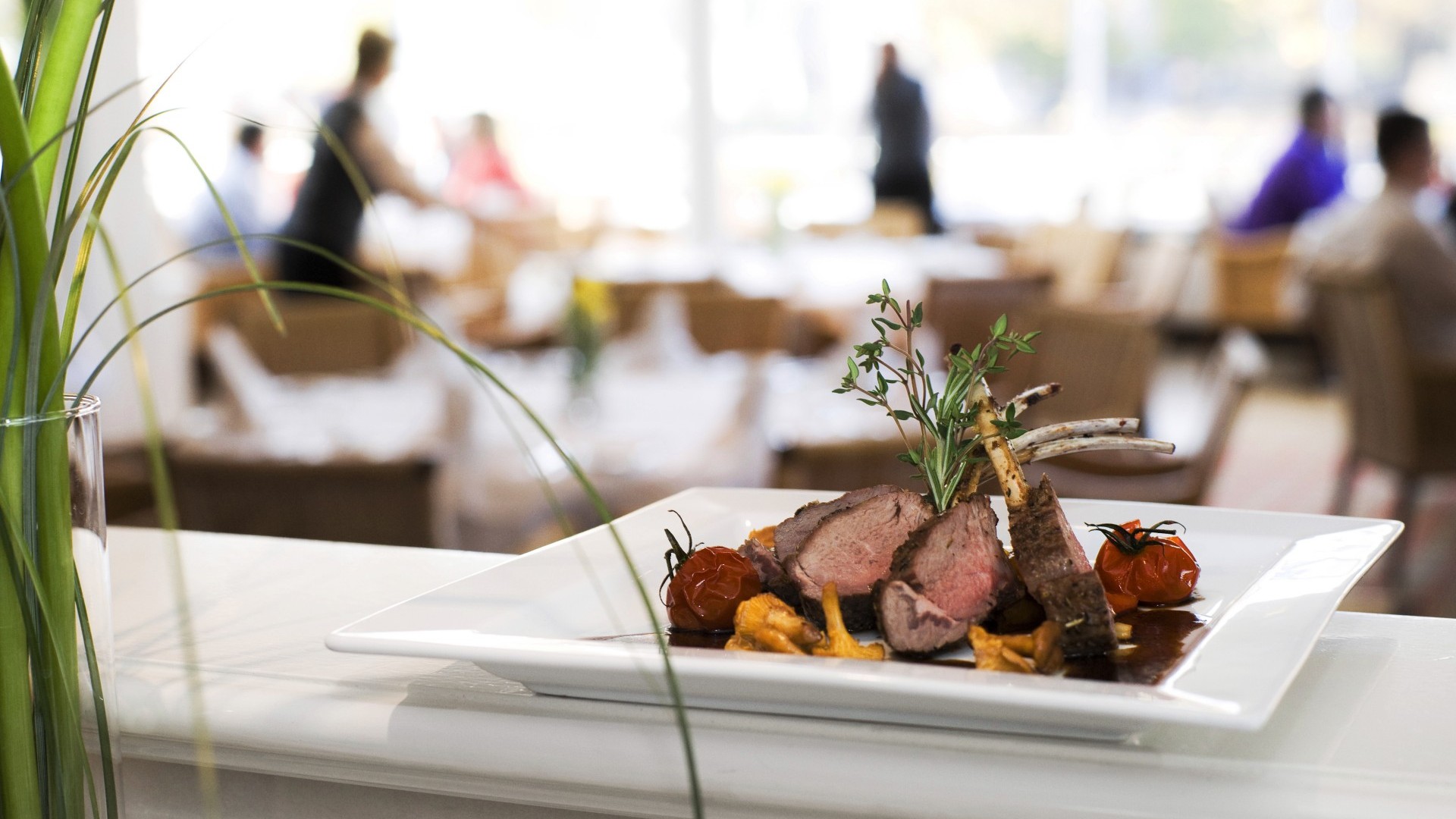 Fleischgericht in Nahaufnahme, im HIntergrund sieht man Gäste