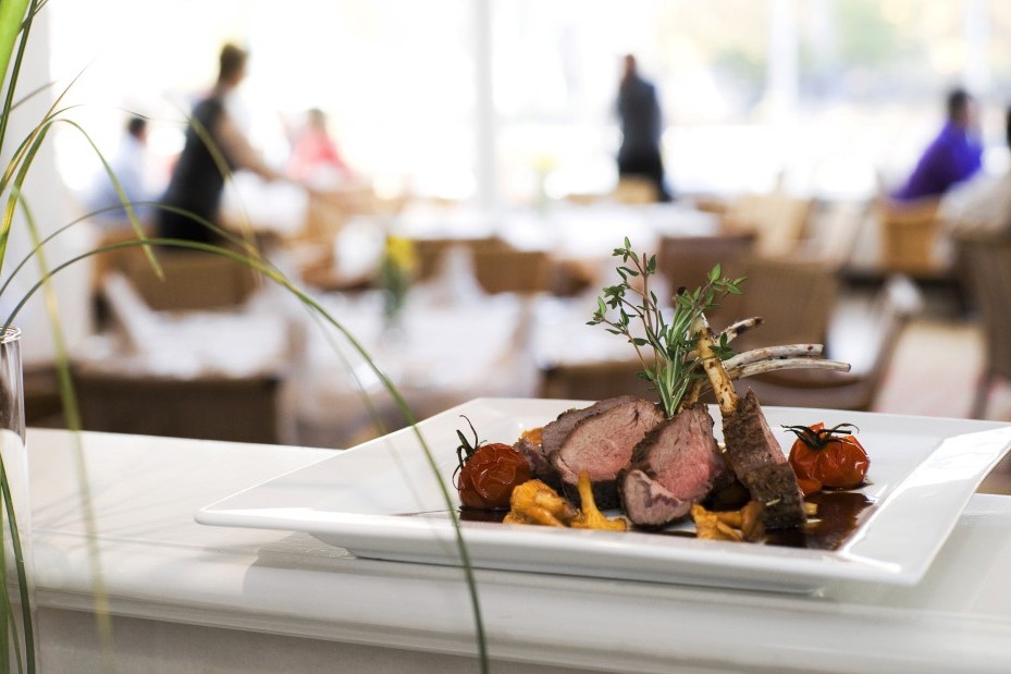 Fleischgericht in Nahaufnahme, im HIntergrund sieht man Gäste