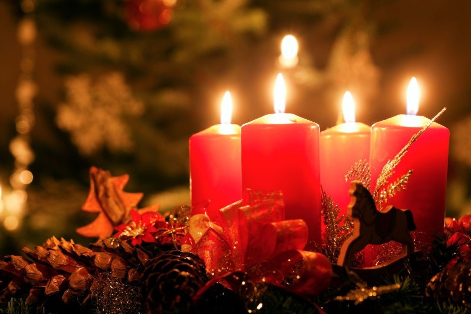 ein Adventskranz mit roten Kerzen die alle leuchten