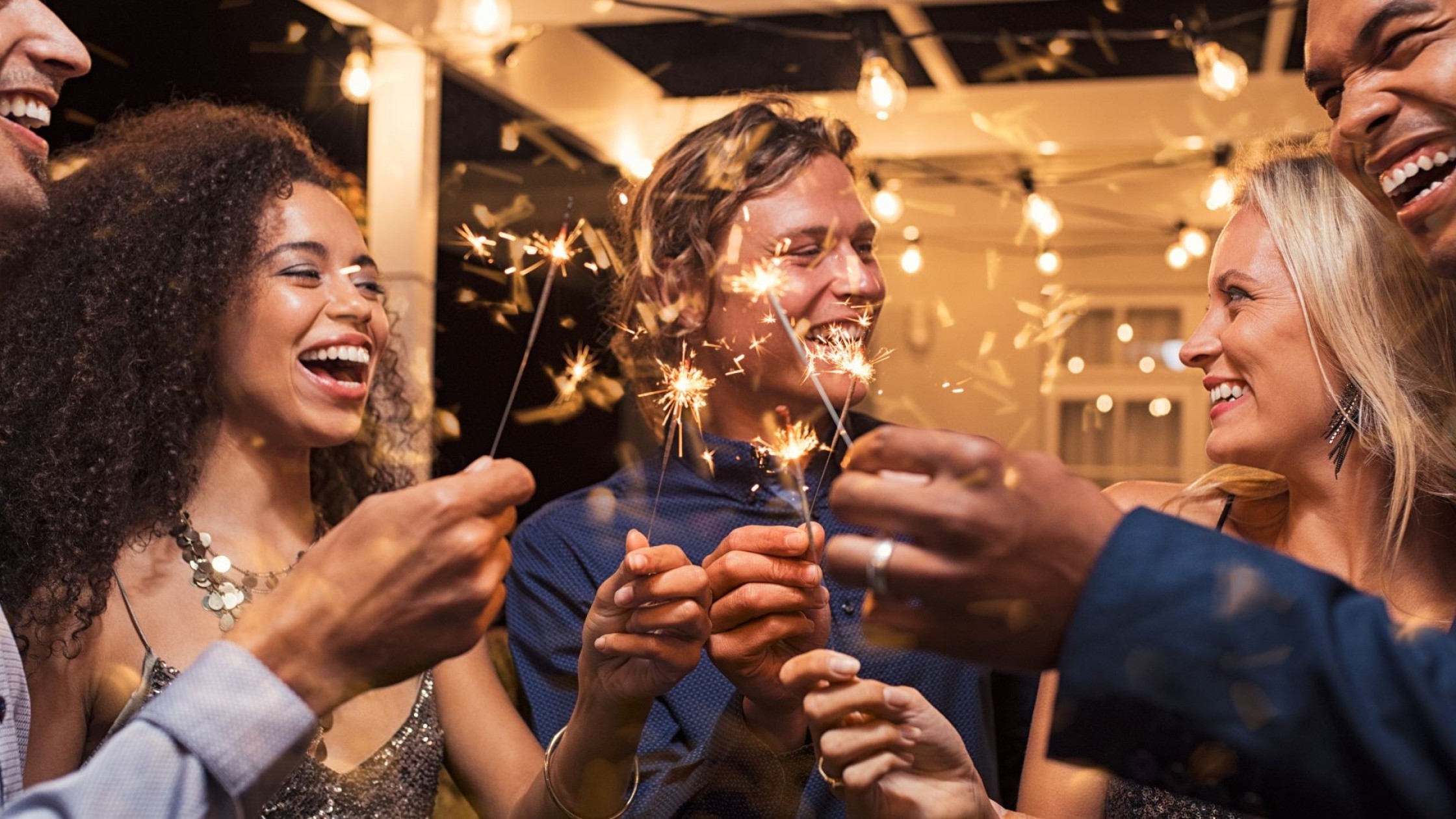Menschen in Partylaune lachen mit glühenden Wunderkerzen in den Händen