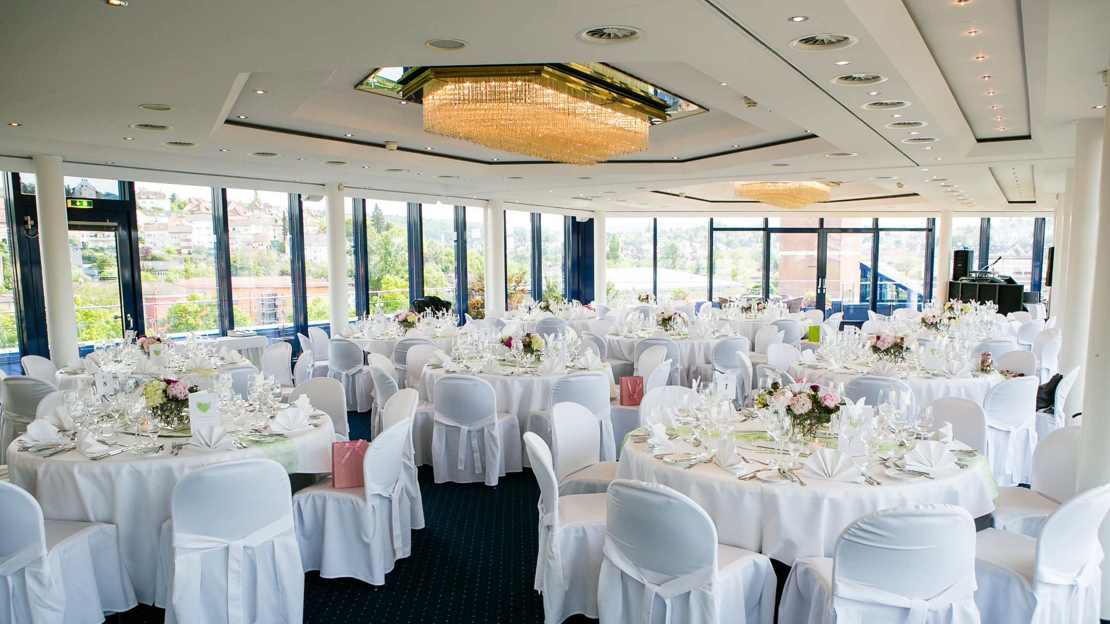 Runde Tische im Dachgarten für eine Hochzeit dekoriert mit weiß und rosa