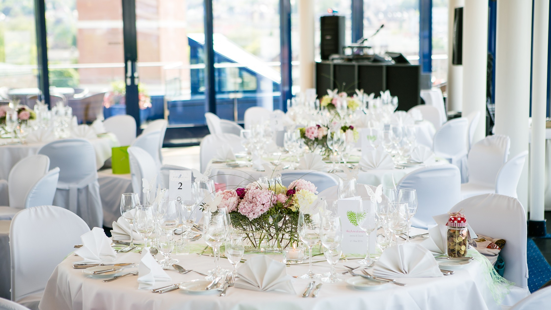 Runde Tische im Dachgarten für eine Hochzeit dekoriert mit weiß und rosa