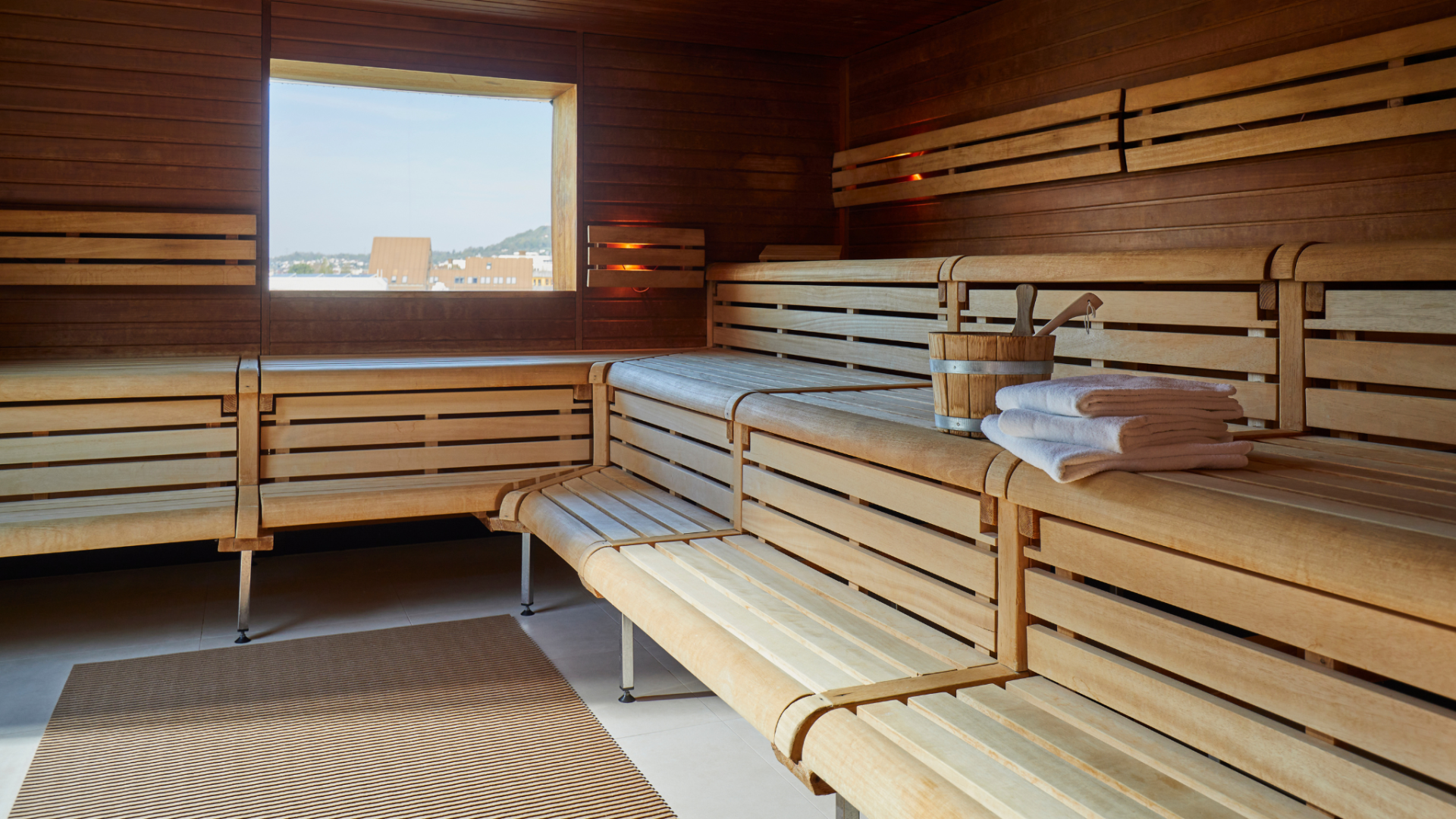 Finnische Sauna mit Holzbänken und einem Fenster mit Aussicht auf die Stadt
