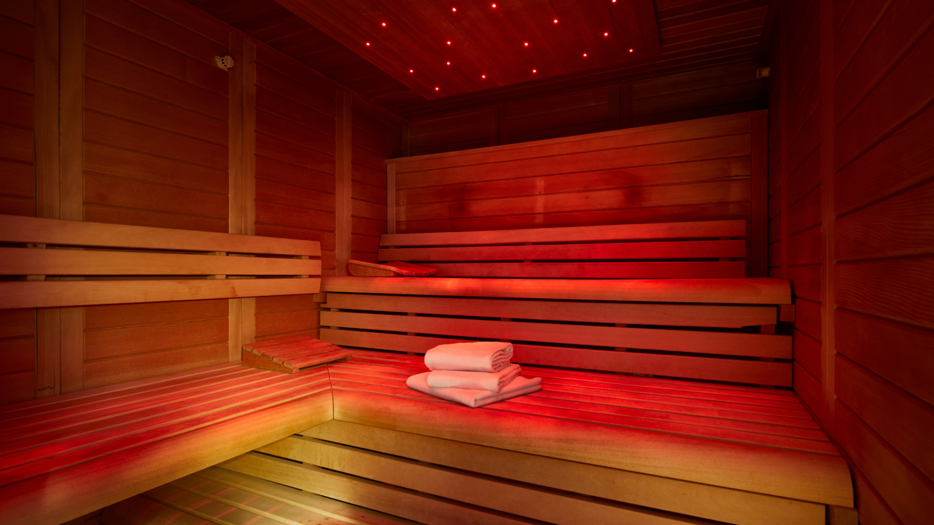Eine Sauna mit Holz-Sitzgelegenheiten und rotem Licht