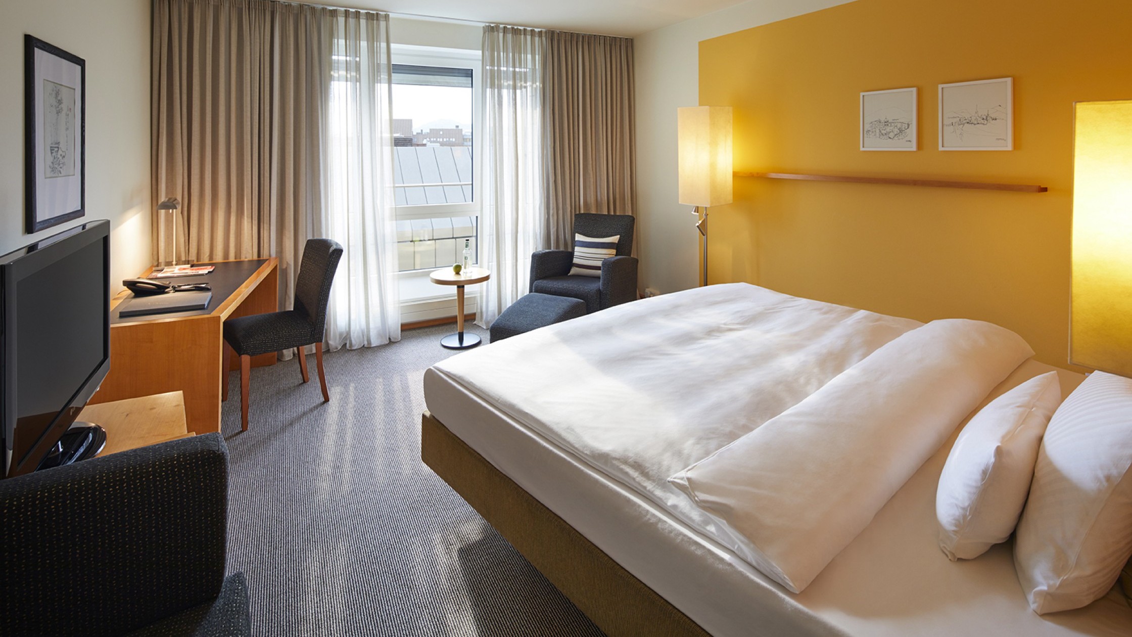 Hotelzimmer mit einem Queen Size Bett und gelber Wandfarbe