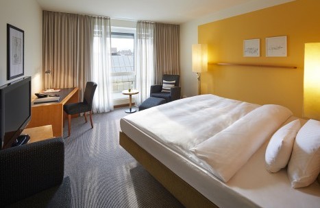 Hotelzimmer mit einem Queen Size Bett und gelber Wandfarbe