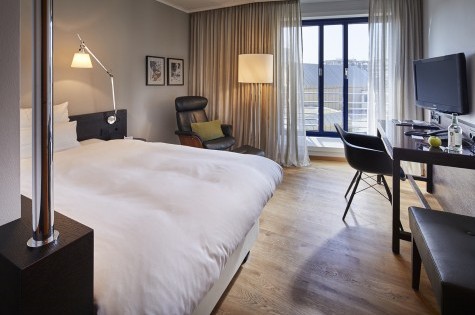 Das Zimmer hat ein Bett in Queen Size Größe mit Holzboden und Schwarzen Sideboard als Schreibtisch