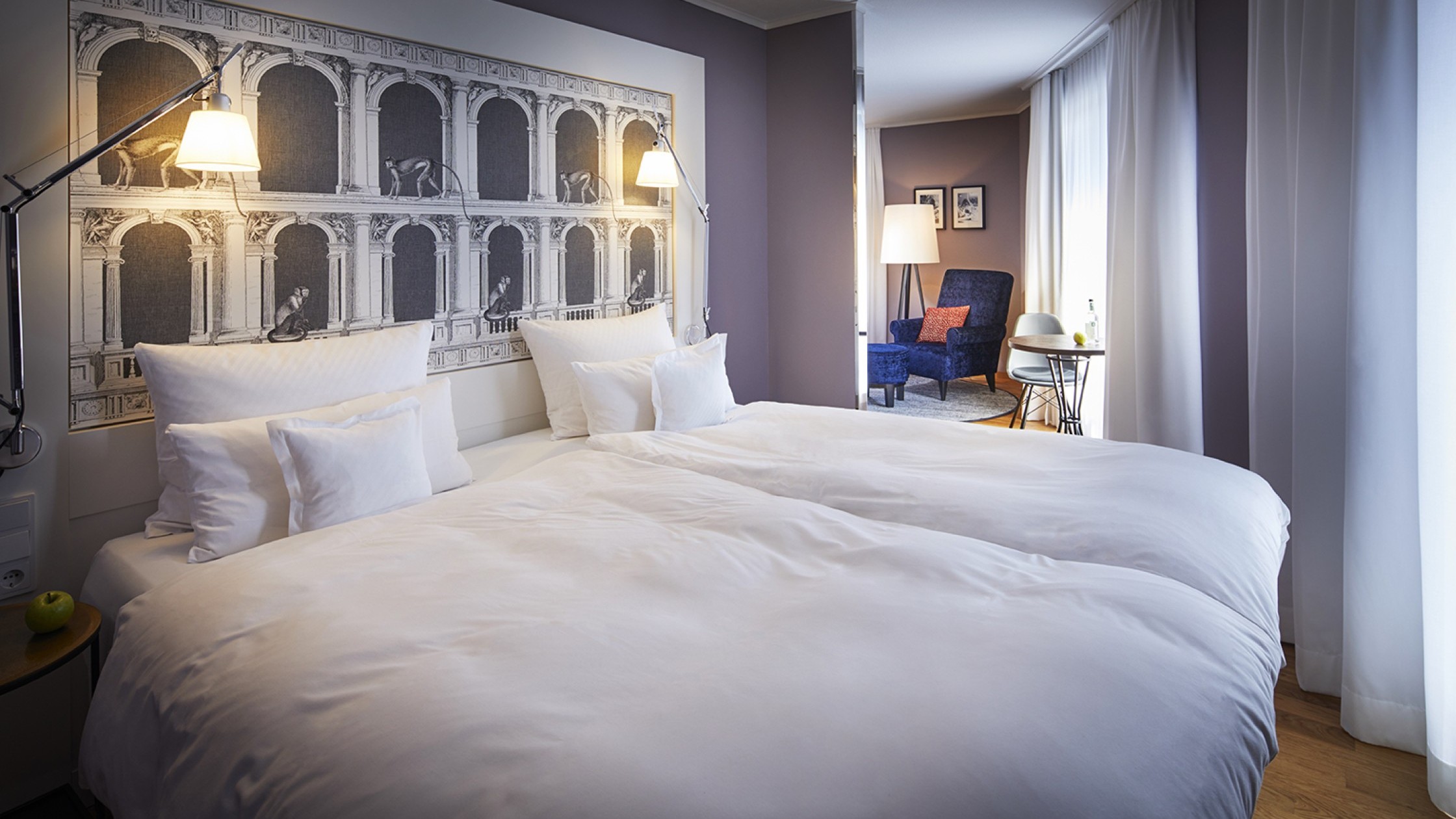 Doppelbett mit schöner Tapette am Kopfende und Blick in den hellen Wohnbereich